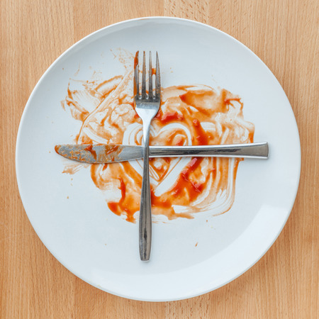 Knife and fork crossed in finish plate and heart shape ketchup, concept of tasty and meaning ready for second plate.の写真素材