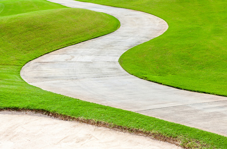 Path curving through green grass in golf course.の写真素材