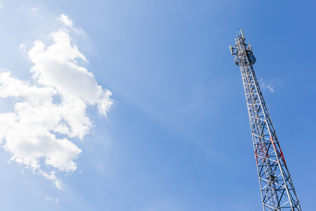 Top of telecommunication tower with fluffy clouds in the sky.の写真素材