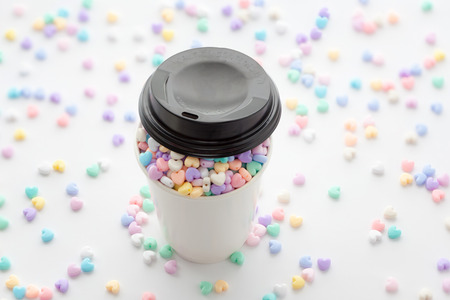 Cup of Love, focus on small colorful pastel heart beads in paper cup with cover and some small heart...