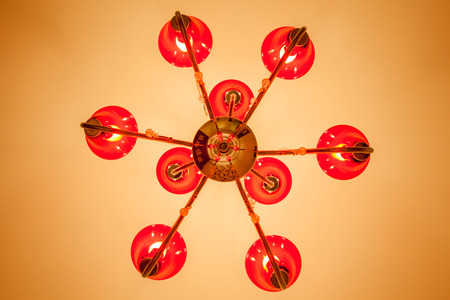 Looking up at the red chandelier with 6 lamps inside decorated on ceiling illuminate warm light room.の写真素材