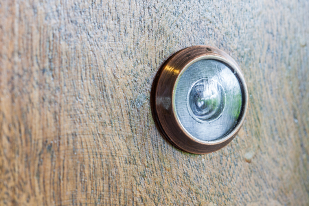 Abstract blur photo of old lens peephole on wooden door background, for security in hotel.の写真素材