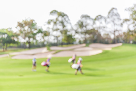 Blurred photo of golf players on green with beautiful nature scene.の写真素材