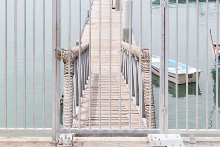Metal entrance door with lock to the private wooden dock into the sea.の写真素材