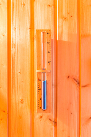 Hourglass or Sandglass hanged on wooden wall of sauna room for timer.の写真素材