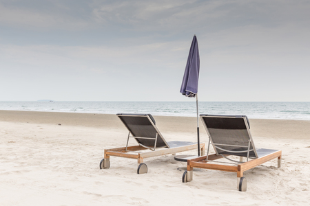 Beach chairs and umbrella on the white sand beach with cloudy sky, relaxation and vacation time.の写真素材
