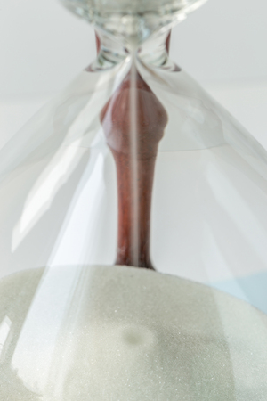 Close up white sand flowing of vintage wooden hourglass on white background, time concept.の写真素材