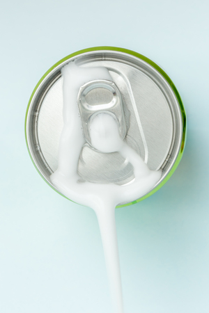 Top view of white soda foam splashing over the aluminum beverage can.の写真素材