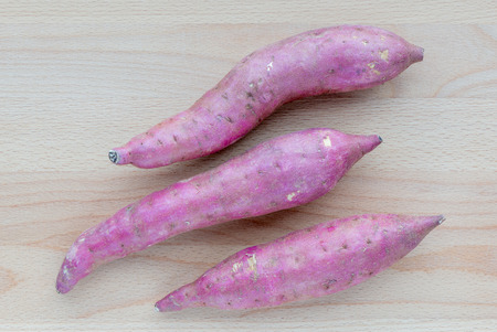 Japanese sweet potatoes on wooden board background, raw material and ingredient concept.の写真素材