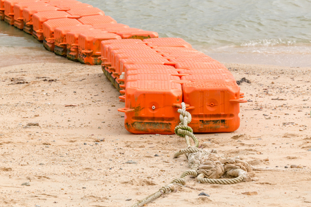 Close up end of orange sea buoys tied on sea beach, marine equipment for marking safety zone.の写真素材