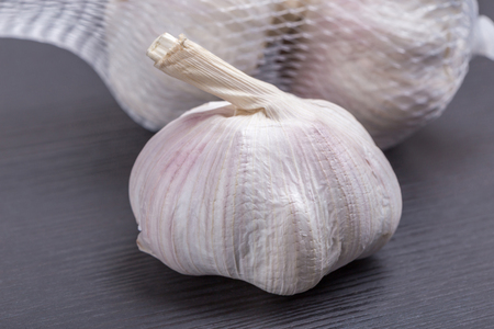 Close up white and clean garlic bulb place on wooden table and the package in blurred background, valuable herbal for healthiness.の写真素材