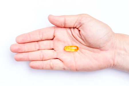 Close up yellow soft gel capsule in male hand with white background, concept of essential oil supplement intake.の写真素材