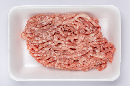 A white foam tray of raw minced pork from supermarket, fresh food ingredients concept.