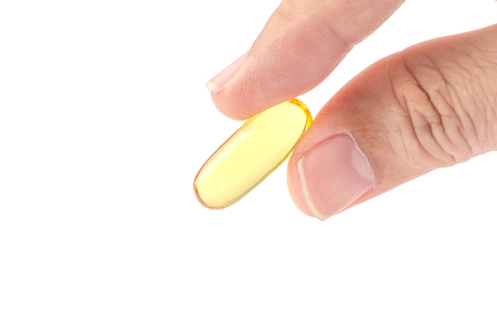 Close up male fingers holding the soft gel capsule on white background, optimal oil supplement in take concept.の写真素材