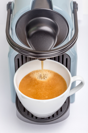 Detail of coffee maker machine pouring hot espresso shot into the white cup, fresh brewing coffee concept.の写真素材