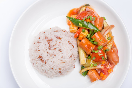 Fried sausages with mixed vegetables in ketchup sauce served with brown rice, healthy eating concept.の写真素材