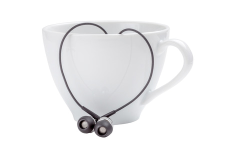 White coffee cup and heart-shape of black headphones on white background, love concept.の写真素材