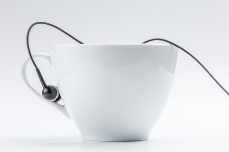 Detail of white coffee cup and black headphones on cup holder isolated on white background, relax time concept.の写真素材