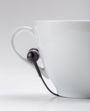 Half white coffee cup and black headphones on cup holder on white background, relax time concept.の写真素材