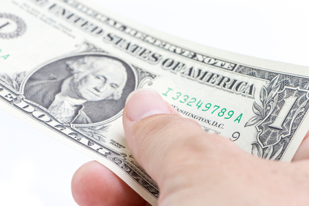 Detail of male hand holding one US dollar banknotes on white background, business and finance concept.の写真素材