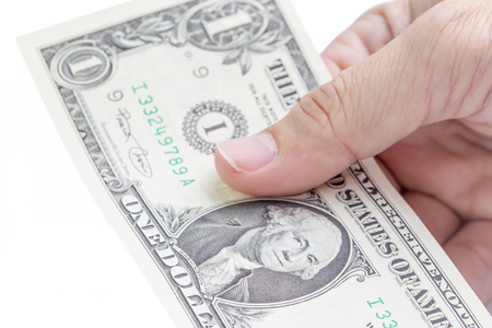 Detail of male hand holding one US dollar banknotes on white background, business and finance concept.の写真素材