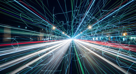 A dynamic long-exposure shot of a city highway at night, creating an abstract web of colorful light trails rushing towards a central vanishing point. The streaks of white, red, and blue light convey concepts of speed, data transfer, and urban energy.の素材