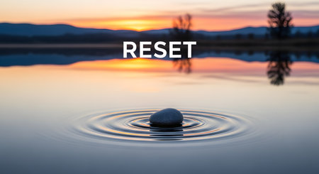 The word 'RESET' is written over a serene landscape. A single smooth stone sits in calm water, creating gentle ripples, with a beautiful sunset over a lake in the background, evoking peace and starting over.の素材
