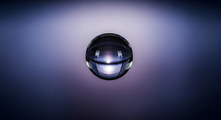 A macro photograph of a single, perfectly spherical water droplet suspended against a smooth purple and blue gradient background. The droplet acts like a lens, refracting light and creating a bright starburst effect, symbolizing purity, clarity, and simplicity.の素材