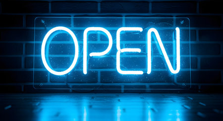 A bright blue neon 'OPEN' sign glows against a dark brick wall. The light from the sign reflects onto the wet-looking floor below, creating an inviting, electric blue ambiance.の素材