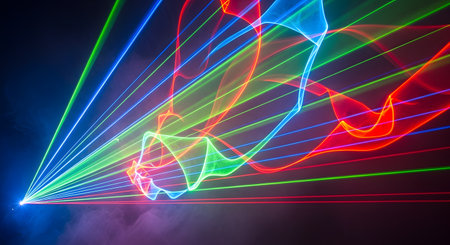 An abstract, vibrant image of a laser light show against a dark background. Bright beams of red, green, and blue light originate from a single point on the left, fanning out and creating complex, swirling patterns and waves, partially illuminated by smoke or fog. This image conveys energy, nightlife, technology, and celebration.の素材