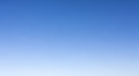 A clear, cloudless sky displaying a beautiful and smooth gradient from deep blue at the top to a light, almost white hue at the bottom. This minimalist background evokes feelings of peace, serenity, and openness.の素材