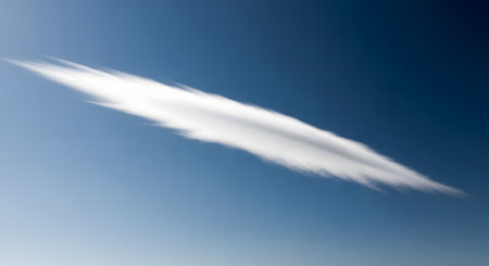 A single, thin, and wispy cirrus cloud streaks diagonally across a deep and clear blue sky. The minimalist and serene image conveys feelings of peace, freedom, tranquility, and isolation.の素材