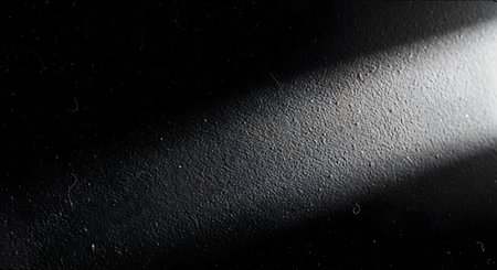 A dark, grainy, black and white background with a heavy texture, similar to film grain or a rough surface. A diagonal beam of light cuts across the top right corner, creating a stark contrast. This image has a moody, noir, or vintage feel.の素材