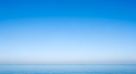 A serene and minimalist landscape featuring a calm blue ocean meeting a clear, gradient sky at the horizon. The tranquil scene evokes feelings of peace, vastness, and simplicity, perfect for a background.の素材