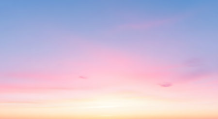 A soft, ethereal, and minimalist background of the sky at sunset or sunrise. The colors blend in a smooth gradient from a light yellow and orange at the horizon to pastel pink, lavender, and light blue. Faint, wispy clouds are visible.の素材