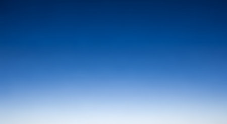 A smooth and clean gradient background transitioning from a deep, rich blue at the top to a pale, almost white hue at the bottom. This versatile abstract background can represent a clear sky, calmness, or a simple, modern design element.の素材