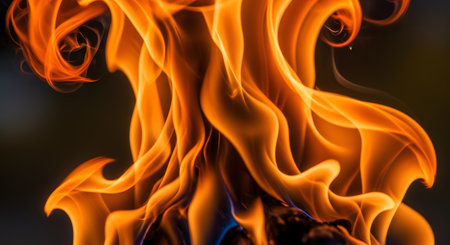An abstract macro photograph of fire, capturing the elegant and dynamic shapes of swirling orange, yellow, and red flames against a black background. The image represents heat, energy, passion, power, and danger. The fluid motion of the flames creates a beautiful and mesmerizing texture.の素材
