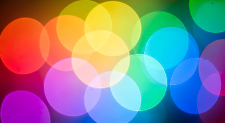 An abstract background of vibrant, overlapping bokeh lights in a rainbow spectrum. The out-of-focus circles of light (red, orange, yellow, green, blue, purple) create a colorful, festive, and blurred effect.の素材