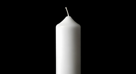 A close-up of the top half of a simple, unlit white cylindrical candle, showing the wick against a solid black background. The image has a minimalist and high-contrast aesthetic.の素材