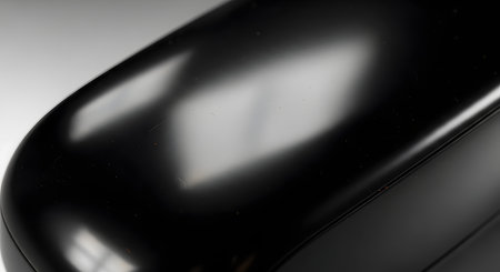 An abstract macro photograph of a sleek, glossy black surface with smooth curves and subtle light reflections. The minimalist and modern image can be used as a sophisticated background for technology, automotive, or luxury product concepts.の素材
