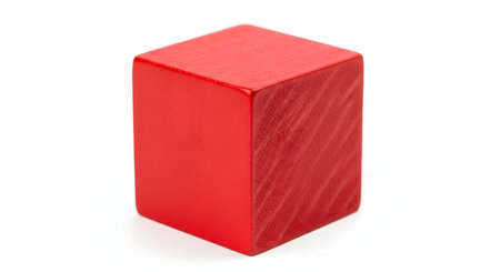 A single red wooden toy block, shaped as a cube, is isolated on a clean white background. The grain of the wood is slightly visible through the red paint. This image represents childhood, toys, and basic geometric shapes.の素材