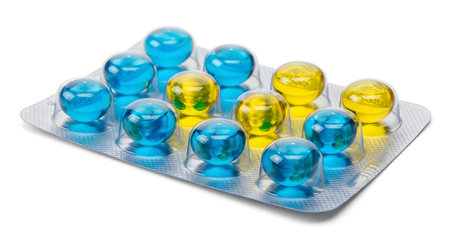 A silver blister pack containing liquid gel capsules, possibly for laundry detergent or bath beads. The orbs are a mix of translucent blue and yellow. The package is isolated on a white background.の素材