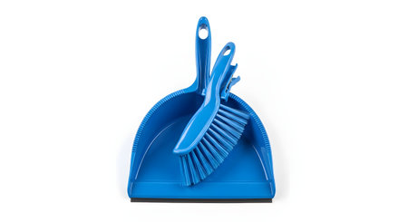 A bright blue plastic dustpan and brush set, isolated on a pure white background. The small hand brush rests inside the dustpan, ready for cleaning.の素材