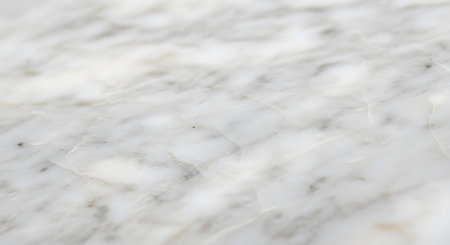 A close-up, angled shot of a white and grey marble surface with natural vein patterns. The image has a shallow depth of field, with the foreground in soft focus, creating an elegant and abstract background texture.の素材