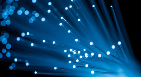 An abstract macro shot of fiber optic cable strands. The tips are glowing with bright blue light, representing high-speed data transmission, technology, and internet connectivity.の素材