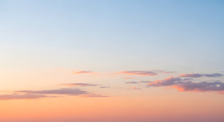 A serene sky filled with soft pink and orange clouds during a pastel sunset. The minimalist and dreamy atmospheric background conveys a sense of calm, peace, and natural beauty.の素材