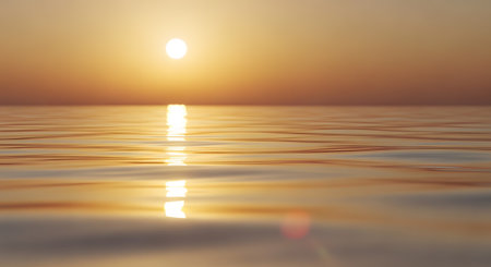 The calm surface of the ocean reflects the golden sun as it sets near the horizon. The gentle ripples in the water create a textured path of light, emphasizing peace and tranquility.の素材
