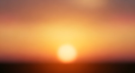 An abstract, blurred background featuring a warm gradient of sunset colors, ranging from deep brown to bright orange and yellow. The soft, out-of-focus texture makes it suitable for design backdrops and overlays.の素材