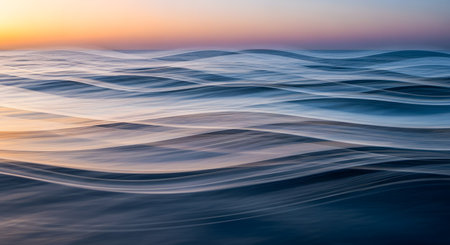 An abstract, long-exposure style image of ocean waves creating smooth, rhythmic curves and motion blur. The soft color palette blends pastel blues, purples, and oranges, evoking a dreamy and artistic seascape.の素材