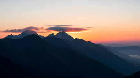 A stunning landscape of a sharp mountain range silhouetted against a vibrant orange and pink sunrise sky. A unique lenticular cloud hovers over the peaks, adding drama to the dawn scene over the rugged terrain.の素材
